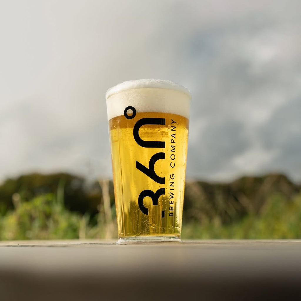 Pint of beer from 360 Brewing Company on a wooden surface with a blurred natural background