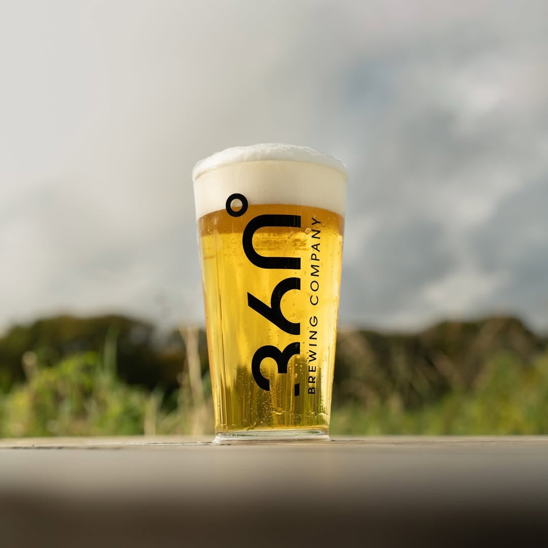 Pint of beer from 360 Brewing Company on a wooden surface with a blurred natural background